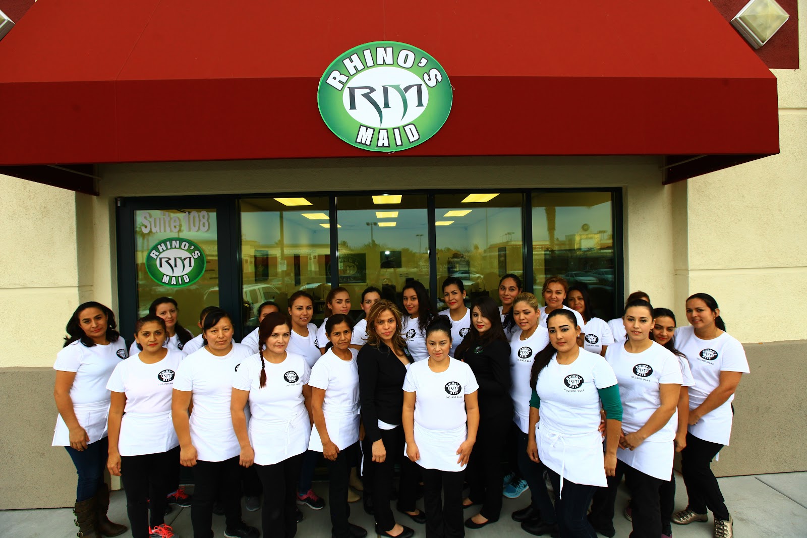 Large team of Rhino's Maid staff posing outside the storefront under a branded awning